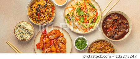 Variety of Chinese food dishes top view on table with chopsticks, light beige background, cuisine of China 132273247