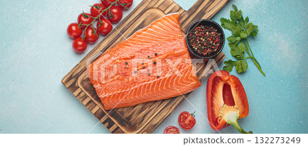 Fresh raw salmon fillet with cooking ingredients on wooden board top view on light blue background 132273249