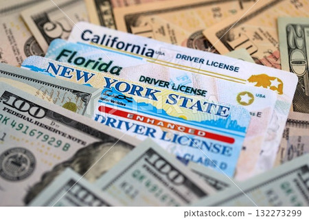 California, Florida and New York state driving licenses among big amount of US dollar bills close up 132273299