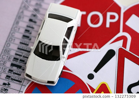 Driving school concept. Toy car and road signs on driver license close up 132273309
