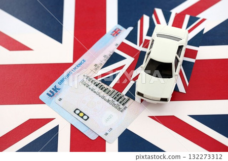 United Kingdom driving license with white toy car on UK flag close up 132273312