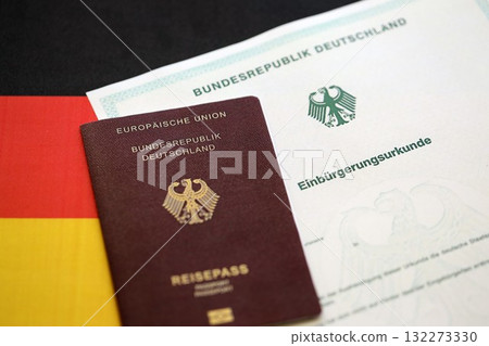 German passport on an official naturalization certificate. Symbolic for successful acquisition of German citizenship close up German passport on an official naturalization certificate. Symbolic for successful acquisition of German citizenship close up 132273330