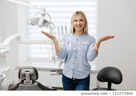 Surprised patient showing something with hands in dental clinic Surprised patient showing something with hands in dental clinic 132273460