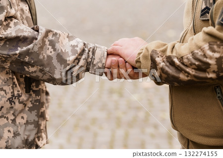 Military Handshake: Soldiers' Camaraderie, Camouflage Uniforms, Respect, Trust, Close-Up, Brown and Gray Tones, Outdoor Setting, Strength, Unity. Military Handshake: Soldiers' Camaraderie, Camouflage Uniforms, Respect, Trust, Close-Up, Brown and Gray Tones, Outdoor Setting, Strength, Unity. 132274155