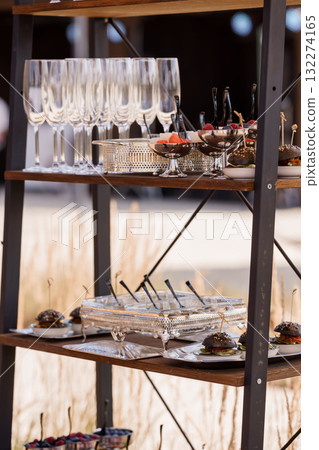 Elegant Catering Display with Wine Glasses and Appetizers on Industrial Shelf, Dark Wood and Silver Tones, Event Setup. 132274165