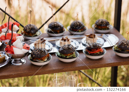 Gourmet Black Burger Skewers Catering Presentation. Delicious Mini Food, Outdoor Event, Silver Platters, Red Watermelon, Rustic Wood Table, Appetizers Gourmet Black Burger Skewers Catering Presentation. Delicious Mini Food, Outdoor Event, Silver Platters, Red Watermelon, Rustic Wood Table, Appetizers 132274166