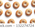 Neatly arranged golden bagels form repeated pattern on solid white. Top-down lighting highlights their texture and sheen. Neural network AI generated 132274724