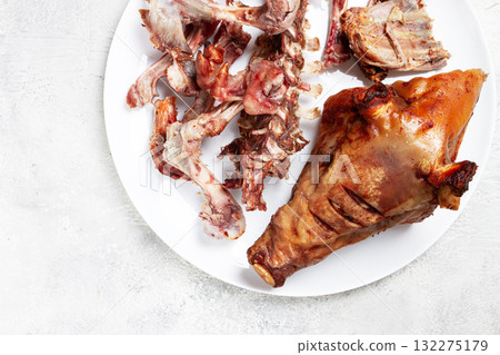 Roast pork head, with remnants of bones and meat, on a white platter, no people, close-up, Roast pork head, with remnants of bones and meat, on a white platter, no people, close-up, 132275179
