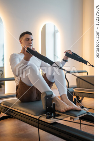Woman Pilates Instructor Gives Guidance to a men Student While They Utilize the Reformers Equipment 132275676