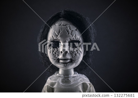 Portrait of a scary cracked doll with black hair on dark background 132275681