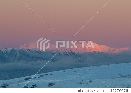 Snow-capped mountain peaks dyed in the morning glow 132276076