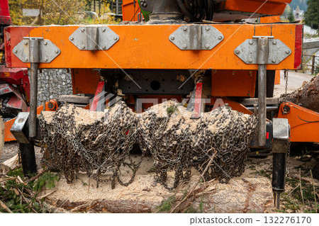 Close up of forestry machine detail with metal chains and sawdust during wood processing Close up of forestry machine detail with metal chains and sawdust during wood processing 132276170