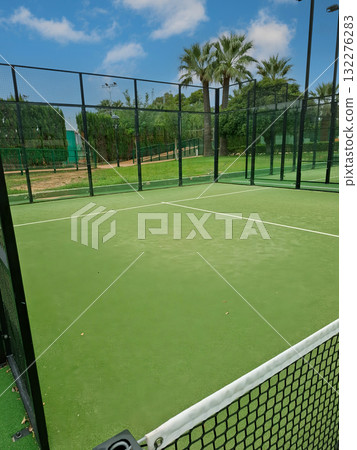 Early morning light shines on the empty tennis court. Trees and greenery frame the area, creating a peaceful outdoor setting perfect for training or leisure activities. 132276283