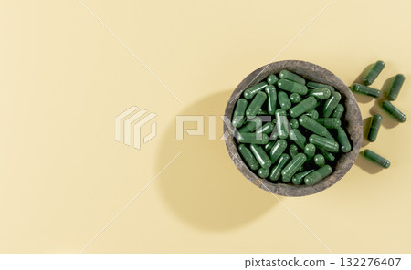 Green spirulina capsules on yellow background. Natural supplement for detox, energy. Copy space. 132276407
