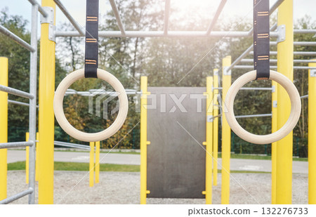 Gymnastic rings in an outdoor gym for calisthenics exercises, selective focus. Gymnastic rings in an outdoor gym for calisthenics exercises, selective focus. 132276733