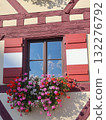 Rustic half-timbered Window With Red Shutters And Colorful Flower Box In Timbered European Facade 132276792