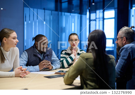 Diverse business team gathered around a table discussing analytics during a meeting in a modern office. Laptop screen shows charts and graphs, symbolizing teamwork, communication, and data driven Diverse business team gathered around a table discussing analytics during a meeting in a modern office. Laptop screen shows charts and graphs, symbolizing teamwork, communication, and data driven 132276990