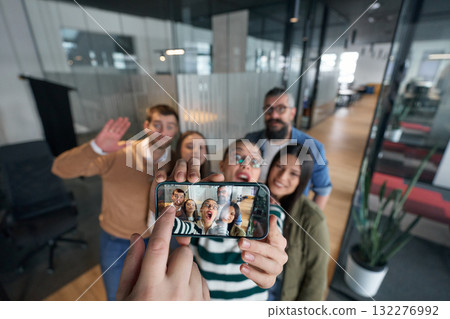 Group of cheerful coworkers taking a selfie together in a modern office environment. Concept of teamwork, friendship, success, and positive company culture. Group of cheerful coworkers taking a selfie together in a modern office environment. Concept of teamwork, friendship, success, and positive company culture. 132276992