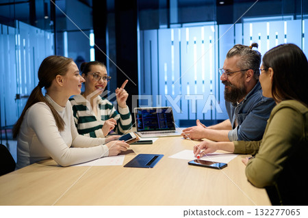 Group of diverse coworkers having a serious discussion around a conference table, led by a bearded male manager, representing teamwork, leadership, and strategy development in a modern business 132277065