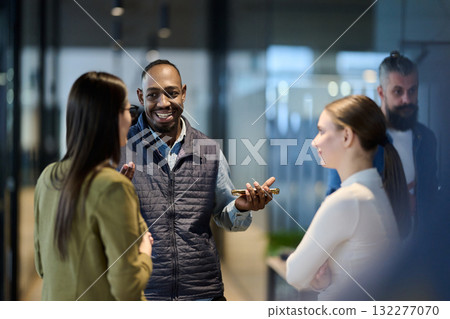 Group of diverse coworkers having a cheerful conversation in a modern office, representing teamwork, communication, leadership, and collaboration in a professional business environment. 132277070