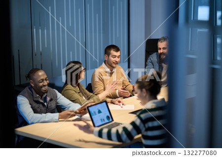 Diverse business team gathered around a table discussing analytics during a meeting in a modern office. Laptop screen shows charts and graphs, symbolizing teamwork, communication, and data driven 132277080