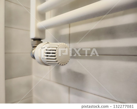 White wall-mounted radiator with an adjustable thermostat valve, featuring a plastic knob with numbered settings for temperature control White wall-mounted radiator with an adjustable thermostat valve, featuring a plastic knob with numbered settings for temperature control 132277081