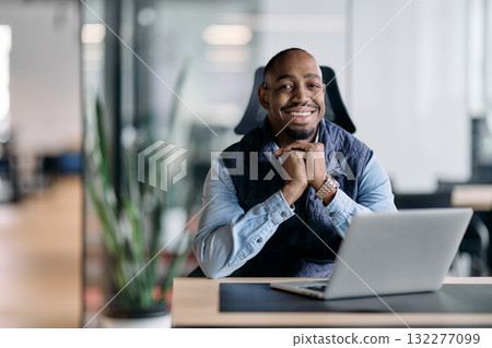 A thoughtful african american businessman sitting at a desk with a laptop in a modern office. He looks away with a reflective expression, symbolizing planning, vision, and future strategy. A thoughtful african american businessman sitting at a desk with a laptop in a modern office. He looks away with a reflective expression, symbolizing planning, vision, and future strategy. 132277099