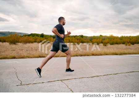 Athletic Man Jogging in the Sun, Preparing His Body for Life's Extreme Challenges 132277384