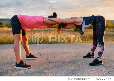 Two Women Athletes Stretching at Sunset in Beautiful Natural Surroundings Two Women Athletes Stretching at Sunset in Beautiful Natural Surroundings 132277446