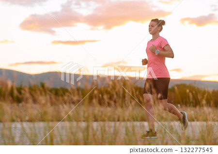 Determined Athlete Running in the Sun amidst Beautiful Nature 132277545
