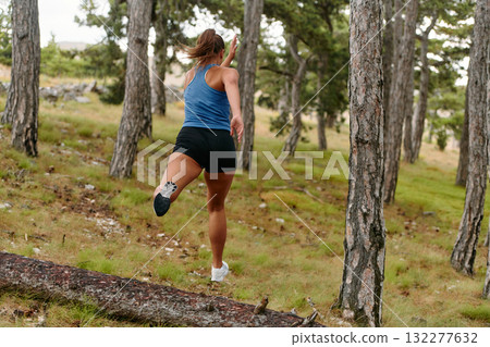Fearless Woman Conquering Wooden Obstacles in the Dangerous Forest Terrain. 132277632