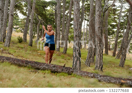 Fearless Woman Conquering Wooden Obstacles in the Dangerous Forest Terrain. 132277688