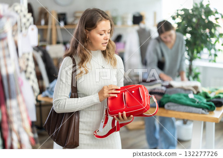 Young woman choosing handbag in clothing store Young woman choosing handbag in clothing store 132277726