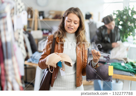 Positive young girl choosing pretty new bra in lingerie store Positive young girl choosing pretty new bra in lingerie store 132277788