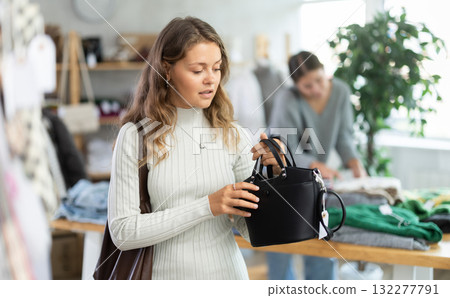 Selective young girl choosing handbag in clothing store 132277791