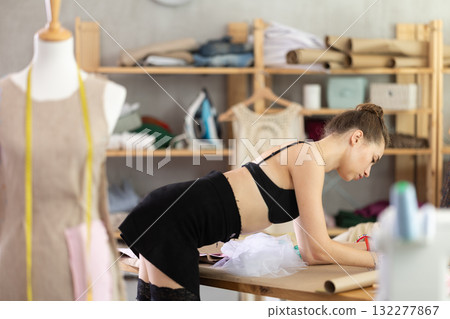 Young woman in stockings drawing pattern on paper Young woman in stockings drawing pattern on paper 132277867