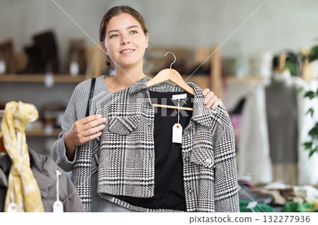 Female shopper selects clothes for autumn winter season in clothing store 132277936