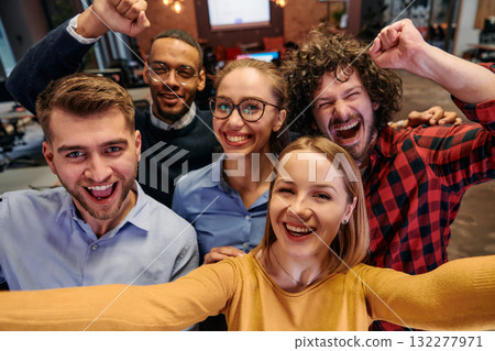 A diverse group of business professionals take a break from their tasks in a modern startup office to capture a creative selfie, showcasing teamwork and a vibrant workplace culture A diverse group of business professionals take a break from their tasks in a modern startup office to capture a creative selfie, showcasing teamwork and a vibrant workplace culture 132277971