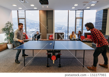 Business colleagues take a break from work to enjoy a game of table tennis, fostering teamwork and camaraderie in the workplace 132277981