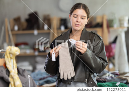 Uncertain young girl choosing winter gloves in clothing store Uncertain young girl choosing winter gloves in clothing store 132278011
