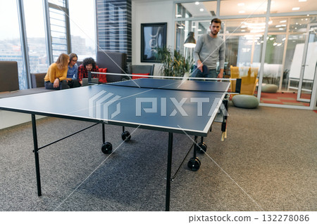 Business colleagues take a break from work to enjoy a game of table tennis, fostering teamwork and camaraderie in the workplace 132278086