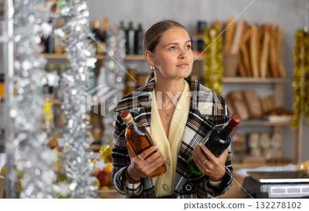 On New Years Eve, girl shopper compare wine and whisky, buys alcoholic beverages 132278102