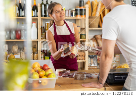Young woman seller offers cheese and meat to buyer Young woman seller offers cheese and meat to buyer 132278138