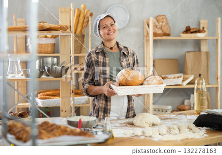 Bakery woman employee holds ready made bread of bread Bakery woman employee holds ready made bread of bread 132278163