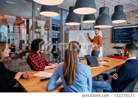 In a corporate setting businessman leads a meeting, passionately presenting a business plan to his attentive team, fostering collaboration and strategic thinking In a corporate setting businessman leads a meeting, passionately presenting a business plan to his attentive team, fostering collaboration and strategic thinking 132278171