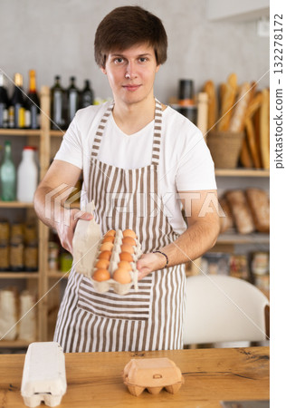 Young male seller offering eggs in grocery 132278172