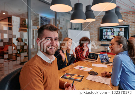 In the vibrant ambiance of a modern startup office, a diverse team of business professionals engage in discussions on various projects and develop new business strategies, epitomizing creativity and 132278173