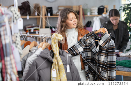 Young woman choosing coat in clothing store Young woman choosing coat in clothing store 132278254