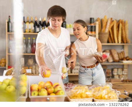 Young married couple buying ripe apples and other products in supermarket 132278262