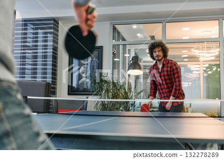 Business colleagues take a break from work to enjoy a game of table tennis, fostering teamwork and camaraderie in the workplace 132278289